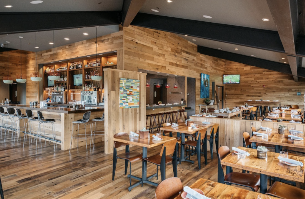 A rustic, wood paneled restaurant dining room with a hightop bar at Versante Hearth + Bar, a top rated restaurant in Park City Utah.