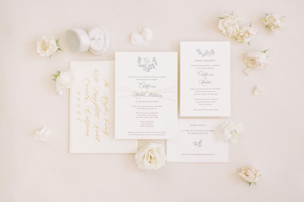 Flat lay of four unique wedding invitation wording examples surround by white flowers.