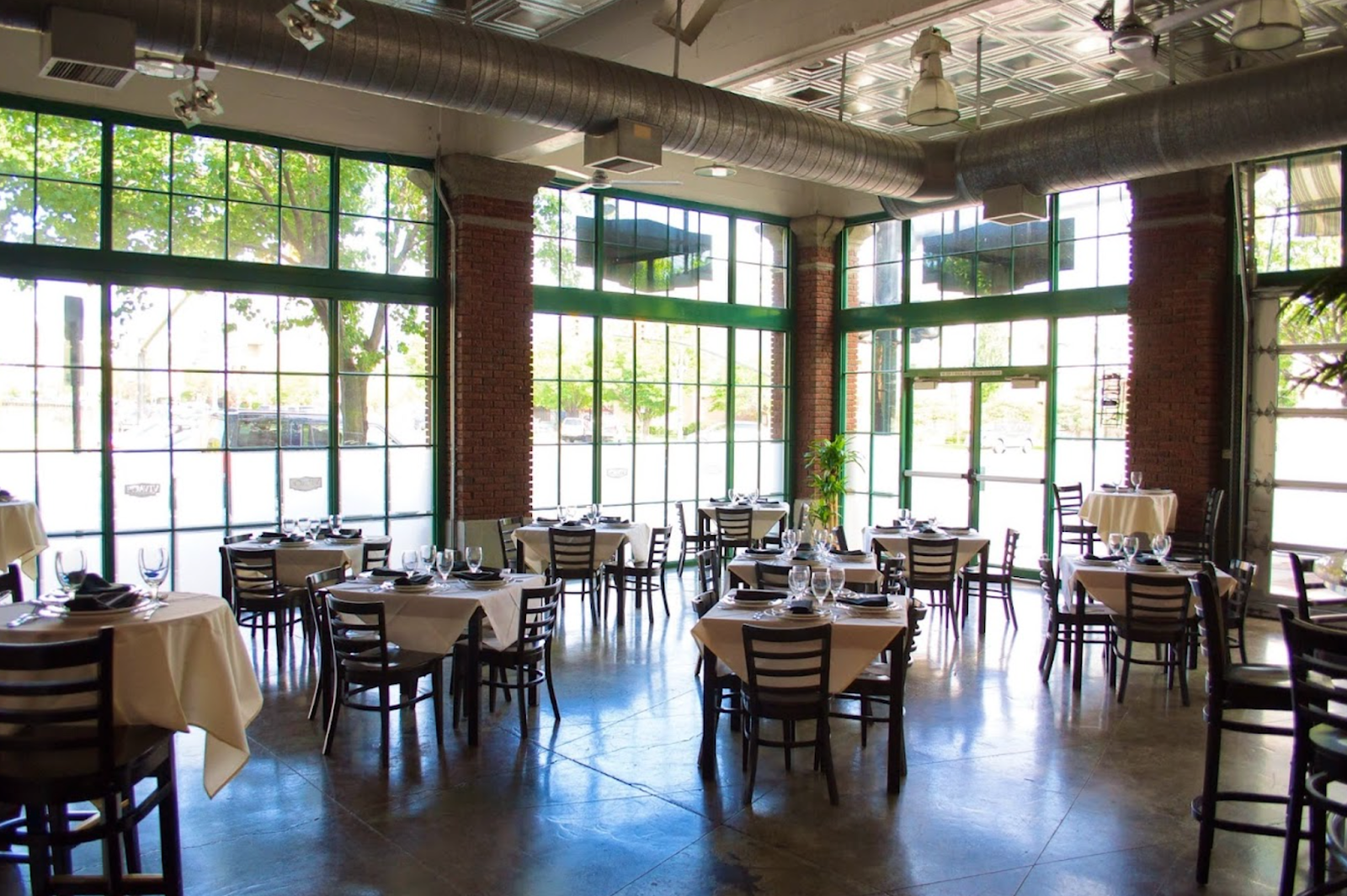 Interior dining room surrounded by floor to ceiling green windows of Cucina Toscana in SLC.